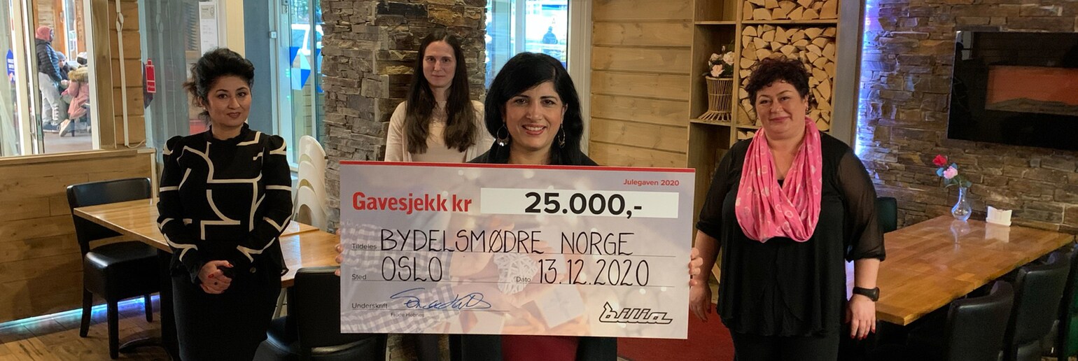 Organisasjonen Bydelsmødre Norge, ved organisasjonsleder Nasreen Beegum, mottar Bilias julegave i form av en gavesjekk pålydende 25.000 kroner. Foto.